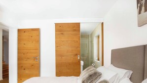 A bedroom with a bed, a wooden door, and a mirror. - Sonnegg Lodge 2.2 Appartement/Fewo Appartement/Fewo by Interhome (Saas-Fee)