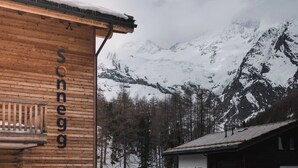 A wooden building with the name 'sonneg' on its facade, surrounded by snow-covered mountains and trees. - Sonnegg Lodge 2.2 Appartement/Fewo Appartement/Fewo by Interhome (Saas-Fee)