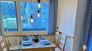 Een eetruimte met een houten tafel gedekt voor vier personen, omringd door comfortabele stoelen.