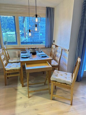 A dining area with a wooden table set for four, surrounded by cushioned chairs. - Bettina Wellness Appartement/Fewo, Dusche oder Bad Bettina 3 by Interhome (Saas-Fee)