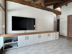 Ein modernes Wohnzimmer mit einem an der Wand montierten Flachbildfernseher, einem Holzkabinett mit Schubladen und einem Marmorboden.