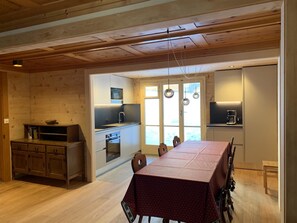 A spacious kitchen with wooden cabinets, a dining table, and a view through the window. - Minga Mal Appartement/Fewo 8-Bettwohnung by Interhome (Saas-Fee)