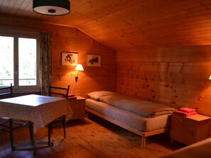 Ein Zimmer in einer Holzhütte mit einem Bett, einem Tisch und zwei Lampen.