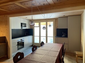 Une cuisine moderne avec un coin repas, un plafond en bois et de grandes fenêtres.