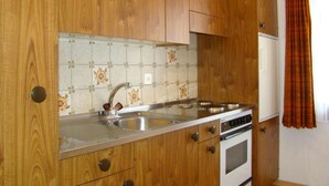 Een keuken met houten kastjes, een roestvrijstalen spoelbak en een inbouwoven.