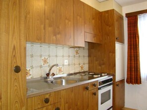 Een keuken met houten kastjes, een roestvrijstalen spoelbak en een inbouwoven.