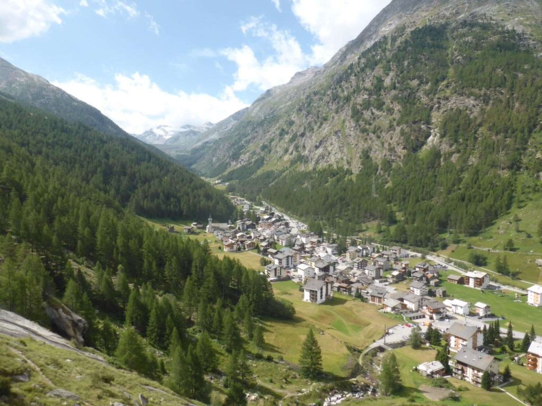 A mountainous village with buildings nestled in the valley, surrounded by dense forests and rocky terrain.