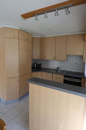 Eine Küche mit Holzausstattung, einer Arbeitsplatte aus Granit und einem eingebauten Backofen.