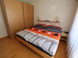 Ein Schlafzimmer mit einem Bett, einem Nachttisch, einer Lampe und einem Kleiderschrank.