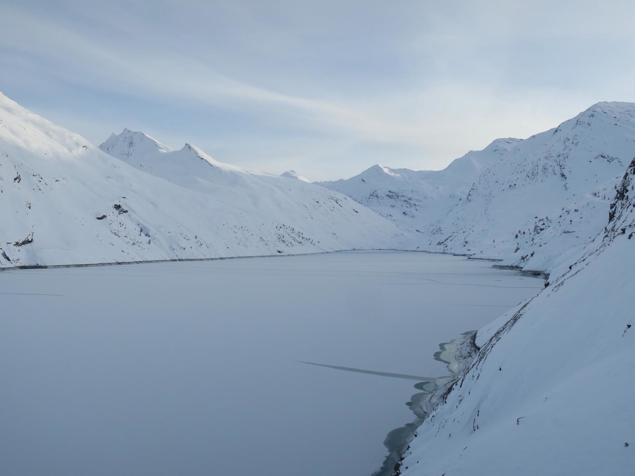 Eine verschneite Berglandschaft mit einem zugefrorenen See.