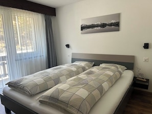 Un dormitorio con una cama, un cuadro en la pared y una mesita de noche con un adorno.