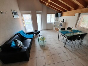 Ein modernes Wohnzimmer mit einer schwarzen Ledersofa, einem Glastisch und einem Essbereich mit einem Tisch und Stühlen.