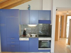 Una cocina con armarios azules, horno empotrado y encimera de granito.