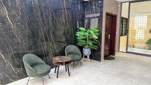 A lobby with a marble wall, two green chairs, a small table, and a potted plant. - Spacious Two-Bedroom Apartment with a Private Balcony and Terrace (Dakar)