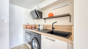 Een kleine keuken met een wasmachine, een spoelbak en een magnetron.