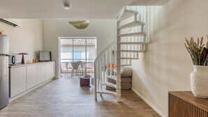 Een moderne keuken met een witte trap, een eethoek met stoelen en een groot raam.