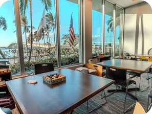 Een vergaderruimte met een groot raam dat uitkijkt over een strand, een Amerikaanse vlag en een tafel met een doos donuts.