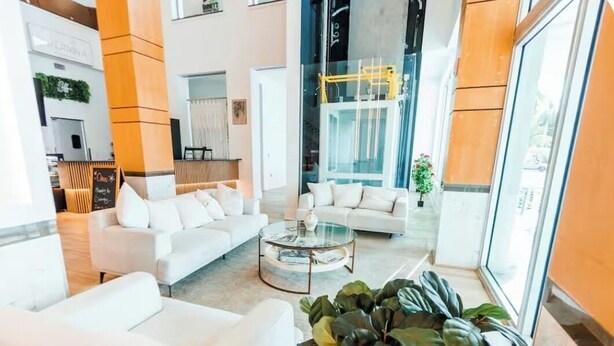 A modern lobby with a white sofa, a glass coffee table, and a large plant. - 24th Floor City View. Luxury Downtown Apartment, Pool, Spa, Gym, Free Parking. (Fort Myers)