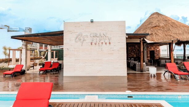 Una piscina con area relax, sedie a sdraio rosse e un cartello con la scritta 'GRAN FIFTY SUITES'.