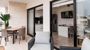 Un'area soggiorno moderna con un tavolo da pranzo, sedie, un divano e una cucina sullo sfondo.