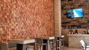Angolo bar con parete in mattoni, televisore a parete e ventilatore a soffitto.