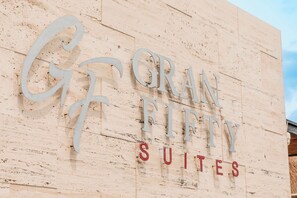 Placa com a inscrição 'GRAN RITTY SUITES' em uma parede texturizada.