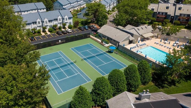 An aerial view of a residential area with two tennis courts, a swimming pool, and a parking lot. - Ground Level Condo 3 Community Pools and Tennis (Rehoboth Beach)
