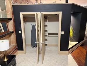Ein Zimmer mit schwarzer Wand, einem Holzschrank, einer Lampe und einer Pflanze.