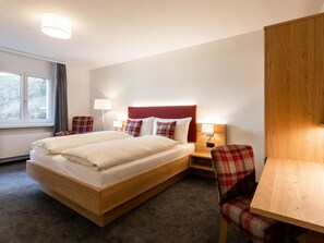 A hotel room with a bed, two bedside tables, a chair, a desk, and a window. - Chalchboda 1 Appartement/Fewo, Dusche und Bad, WC, 7-Bettwohnung by Interhome (Arosa)