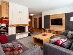 A modern living room with a fireplace, grey sofas, a coffee table, and a flat-screen TV mounted on the wall. - Chalchboda 1 Appartement/Fewo, Dusche und Bad, WC, 7-Bettwohnung by Interhome (Arosa)