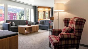 A modern living room with two sofas, a coffee table, and a plaid armchair. - Chalchboda 1 Appartement/Fewo, Dusche und Bad, WC, 7-Bettwohnung by Interhome (Arosa)