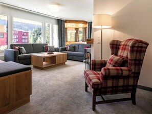 Ein modernes Wohnzimmer mit zwei Sofas, einem Couchtisch und einem karierten Sessel.