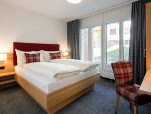 A hotel room with a bed, a chair, a desk, and a window with curtains. - Chalchboda 1 Appartement/Fewo, Dusche und Bad, WC, 7-Bettwohnung by Interhome (Arosa)