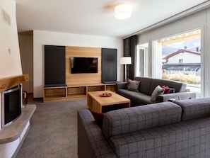 A modern living room with a flat-screen TV, a fireplace, a sofa, and a coffee table. - Chalchboda 1 Appartement/Fewo, Dusche und Bad, WC, 7-Bettwohnung by Interhome (Arosa)