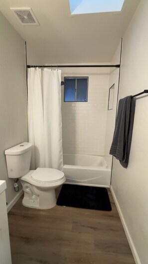 Une salle de bain de taille réduite, équipée de toilettes, d’une douche et d’une baignoire.