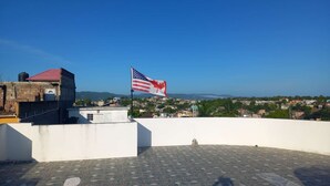 Eine Dachterrasse mit einer Flagge, Blick auf eine Stadtlandschaft und einem gefliesten Boden.