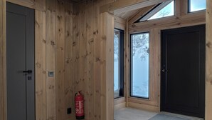 Een houten interieur met een brandblusser, een deur en een raam met uitzicht op sneeuw.