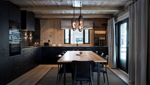 Een moderne keuken met een houten plafond, zwarte kasten, een centraal eiland en hangende lampen.