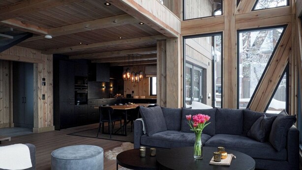 Een modern interieur met een eethoek, keuken en woongedeelte, voorzien van houten balken en grote ramen.