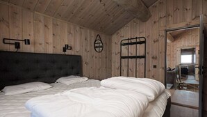 Een slaapkamer met een groot bed, houten wanden en een plafond met zichtbare balken.