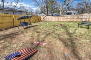 A backyard with a swing set, a bench, and American flag decorations. - New! Ivy Luxury Home Near Airport And Downtown (East Point)