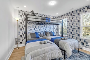 A modern hotel room with two beds, a bunk bed, a standing lamp, and a large window. - New! Ivy Luxury Home Near Airport And Downtown (East Point)