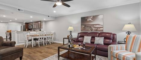 A modern living room with a sofa, armchair, coffee table, and dining area.