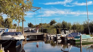 Eine friedliche Marina mit vertäuten Booten, einer Fußgängerbrücke und Bäumen im Hintergrund.