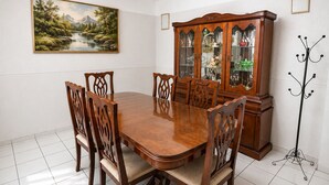 A dining room with a wooden table and chairs, a china cabinet, and a painting on the wall.