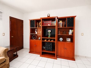 Una habitación con una estantería de madera, una puerta y suelo de baldosas.