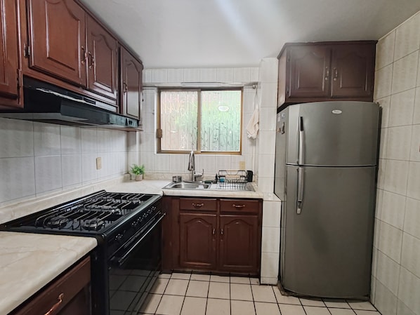 A kitchen with a stove, oven, sink, and a refrigerator.