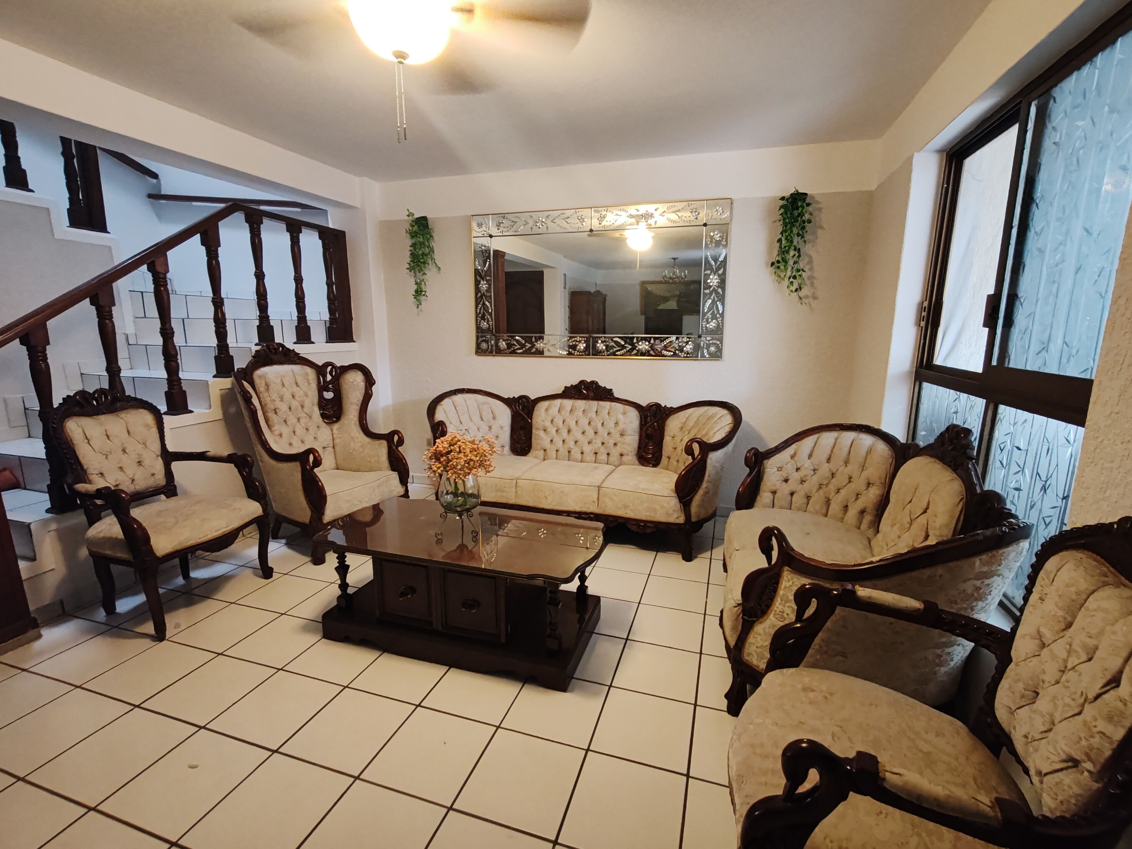A living room with a sofa set, a coffee table, and a staircase.