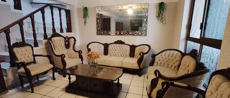 A living room with a sofa set, a coffee table, and a staircase.