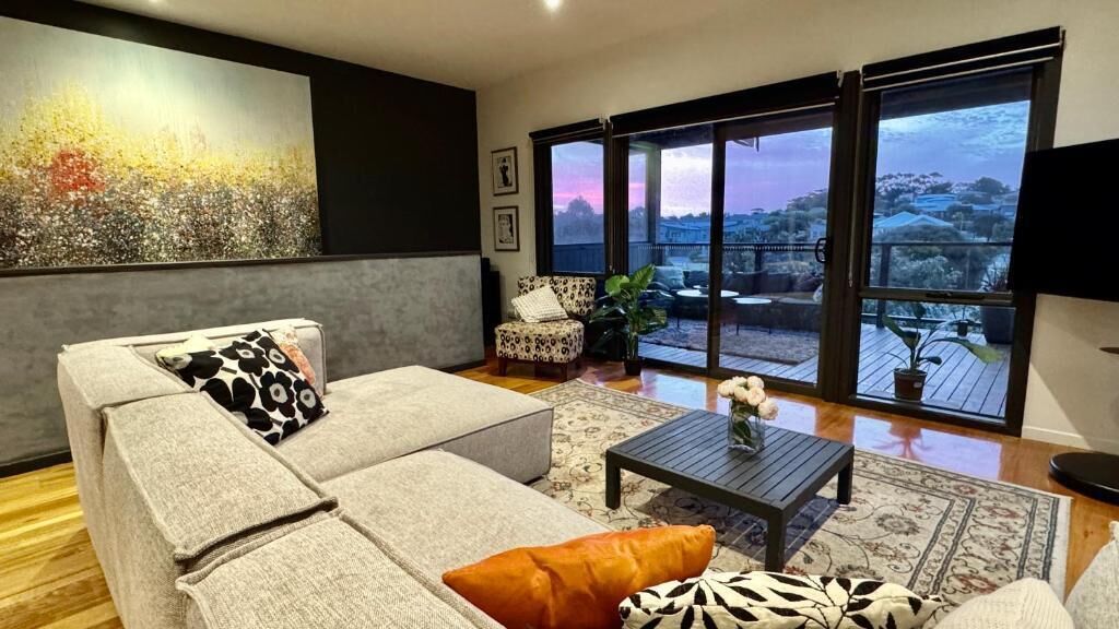 A living room with a sofa, armchair, coffee table, and a large window with a view.